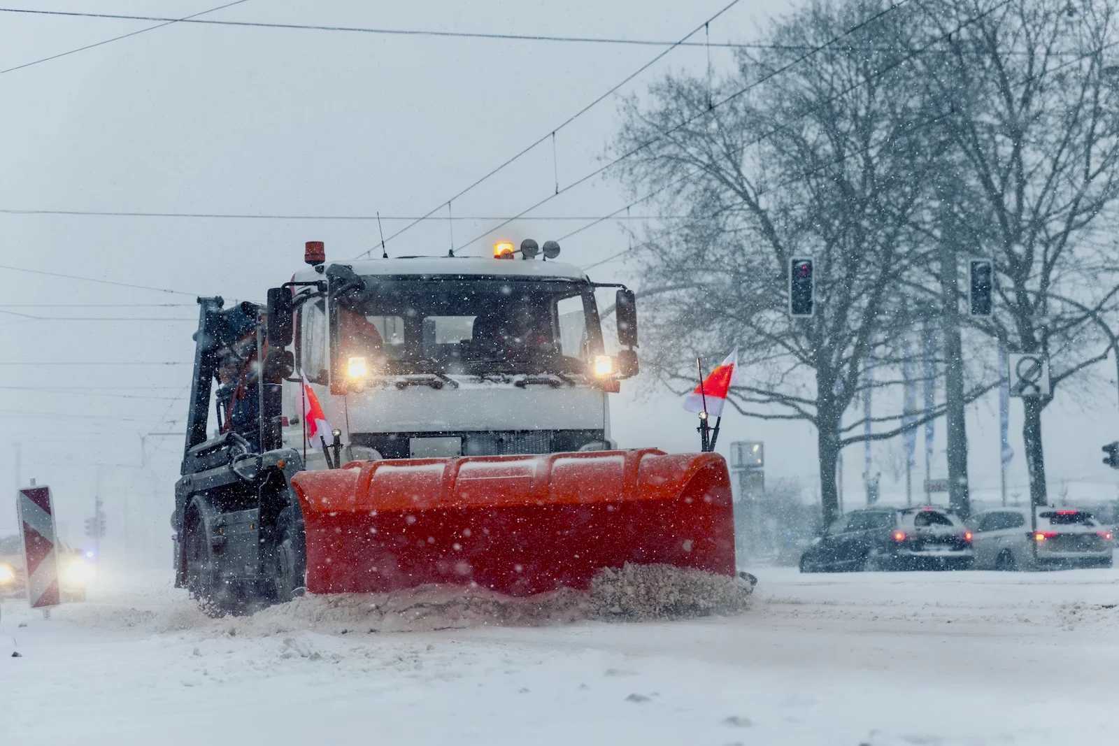 Snowplow truck removing dirty snow from city street on highway during heavy snowfalls.